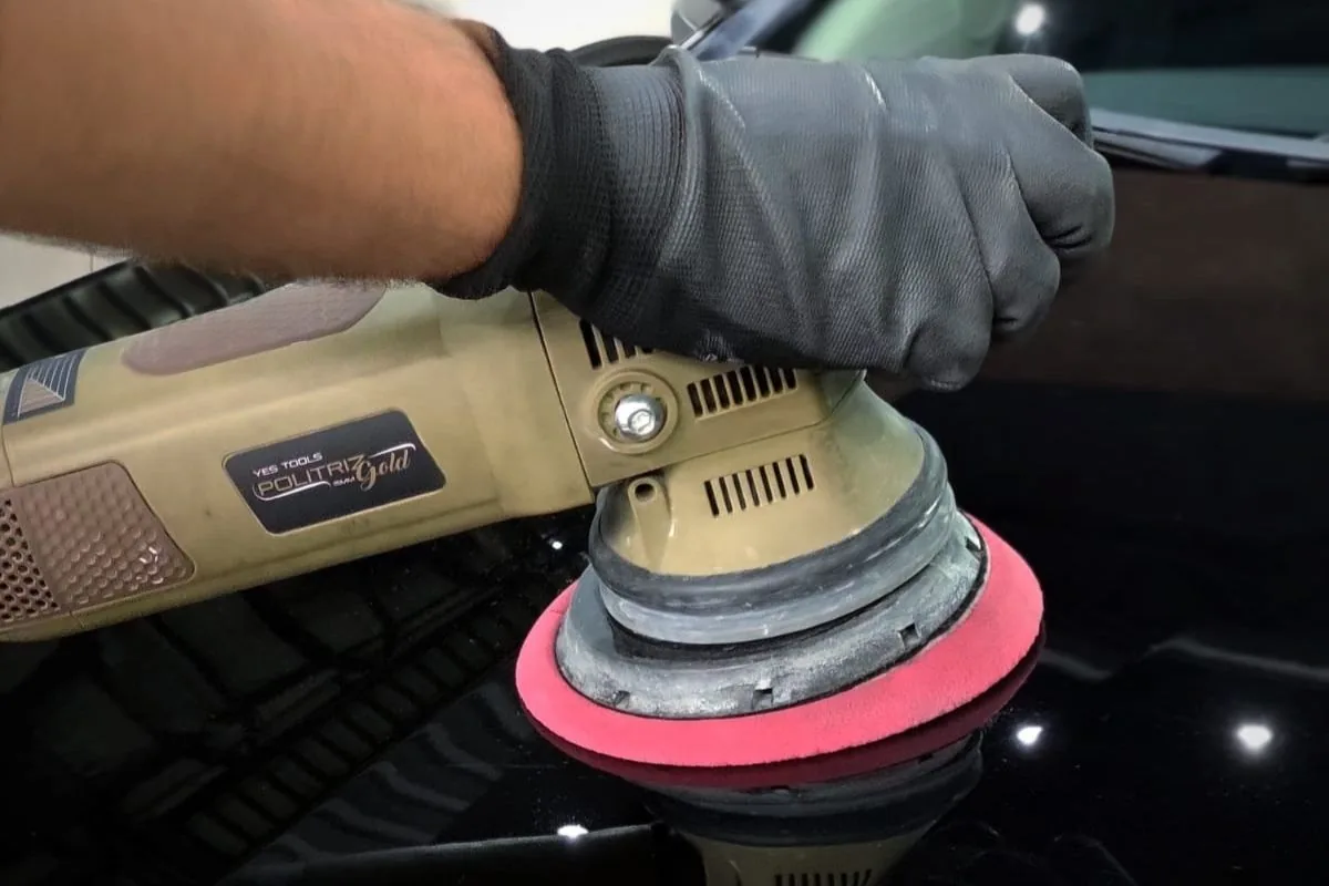Politriz em uso sobre pintura preta durante etapa de refino no Spa do Automóvel